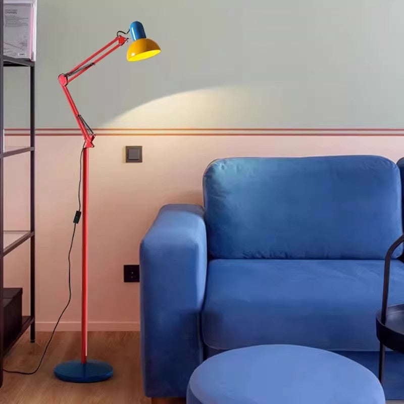 Bunte Stehlampe mit rotem Arm und gelbem Schirm neben blauem Sofa im Wohnzimmer
