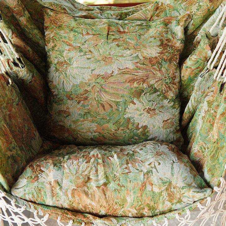 Woven hammock chair with padded floral cushions and macramé fringe Kalsten