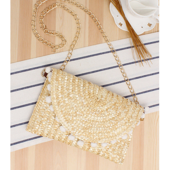 Clutch made of handwoven natural material with decorative pompons Kalsten