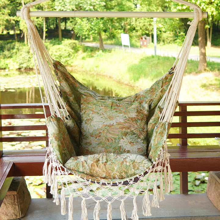 Woven hammock chair with padded floral cushions and macramé fringe Kalsten