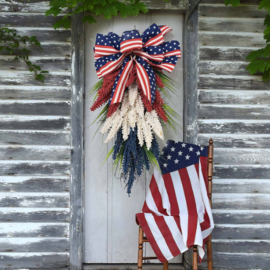 Independence Day tapering teardrop door swag with wired stars-and-stripes bow and textured faux floral sprays Kalsten