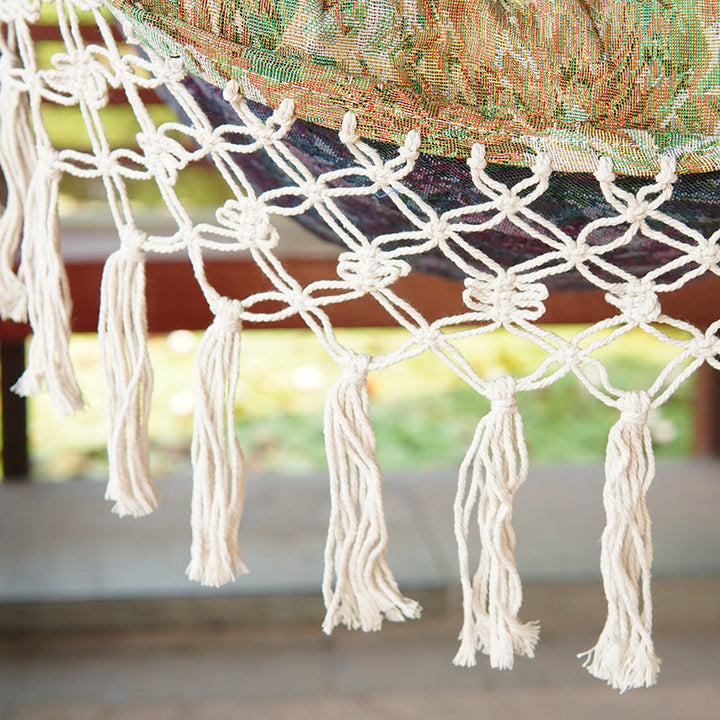 Woven hammock chair with padded floral cushions and macramé fringe Kalsten